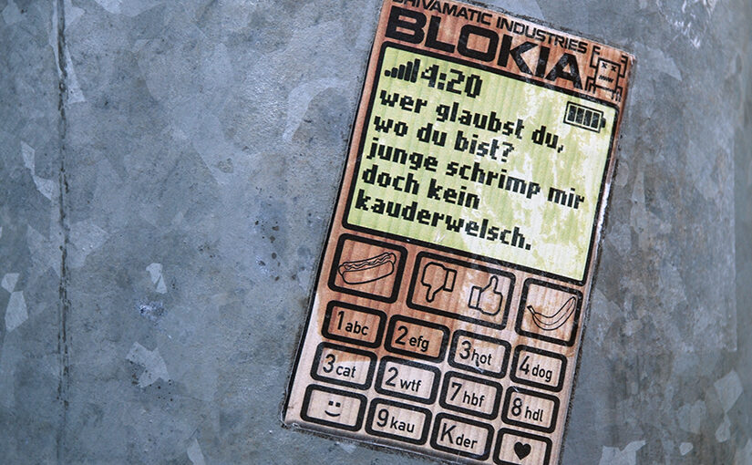 Nokia Handy Parodie als Aufkleber auf einem Laternenpfahl: wer glaubst du, wer du bist? junge schrimp mir doch kein kauderwelsch